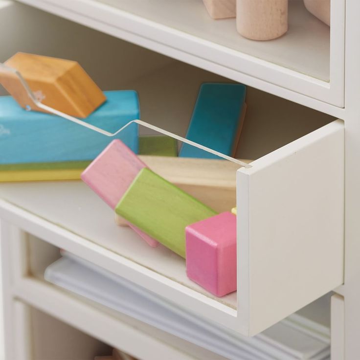 a toy car is in the drawer of a white cabinet with drawers on both sides