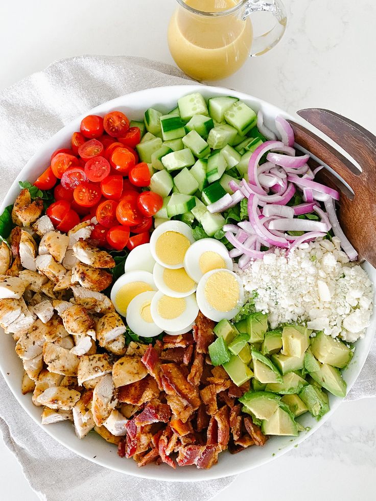 a salad with hard boiled eggs, tomatoes, cucumbers, onions and chicken