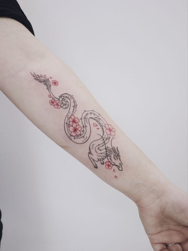 a woman's arm with a tattoo on it that has two snakes and flowers