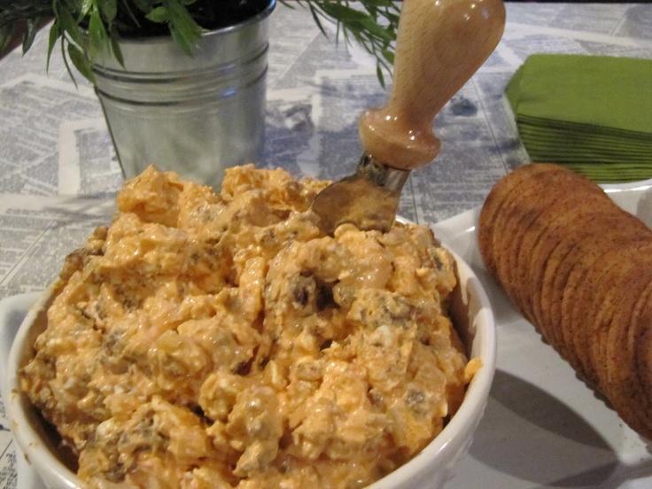 a white bowl filled with food sitting on top of a table next to a wooden spoon