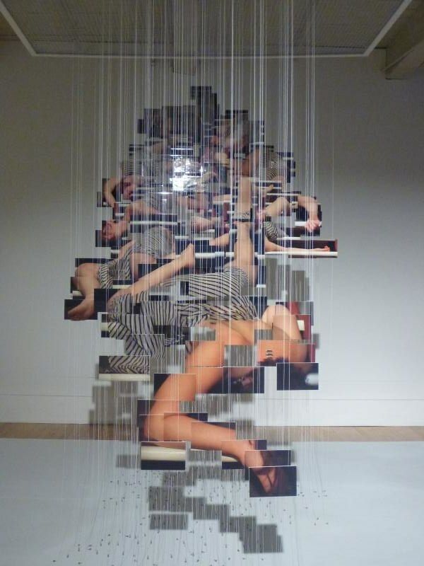 an art work with multiple images on the wall and in the background is a woman's body