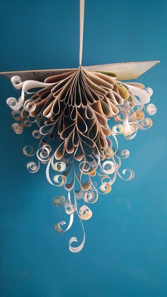 an origami bird hanging from a string on a blue wall with white swirls