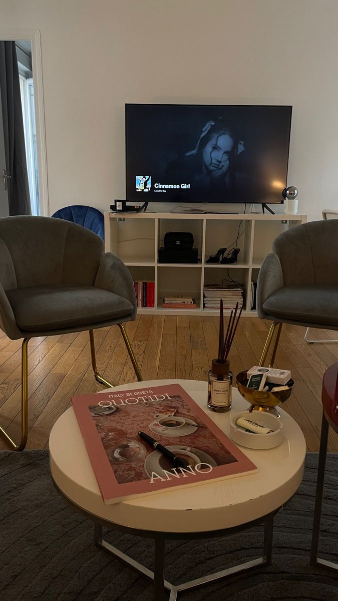 a living room with two chairs and a coffee table in front of a flat screen tv