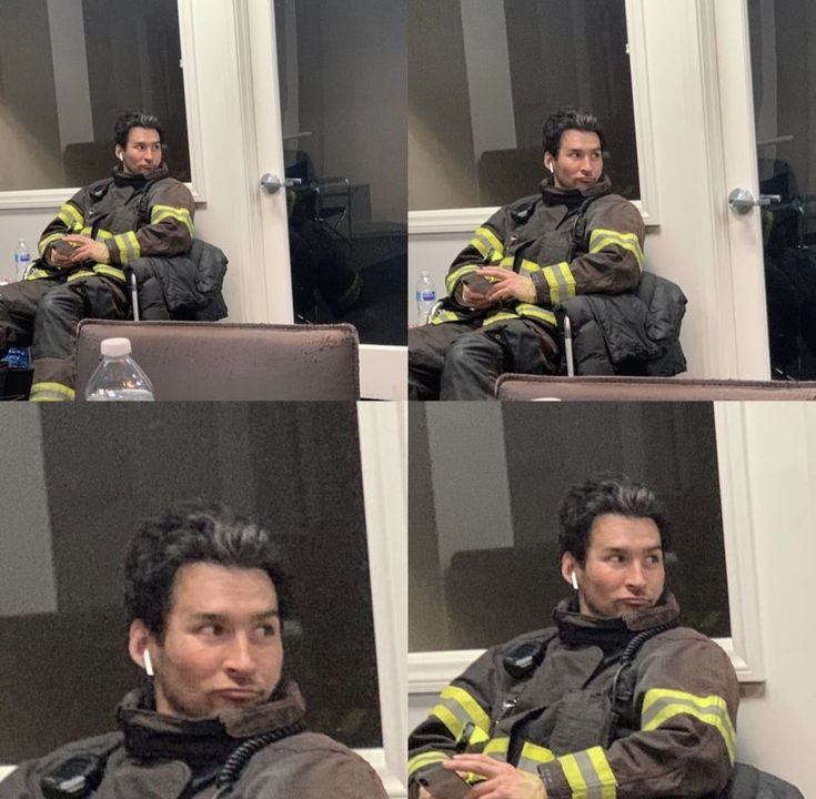 the man is sitting down with his head in his hands and wearing a fireman's jacket