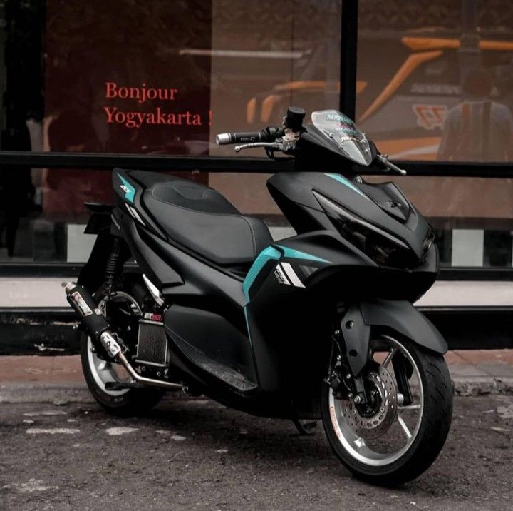 a black motorcycle parked in front of a glass storefront with the words bonjou yoyaskarta on it