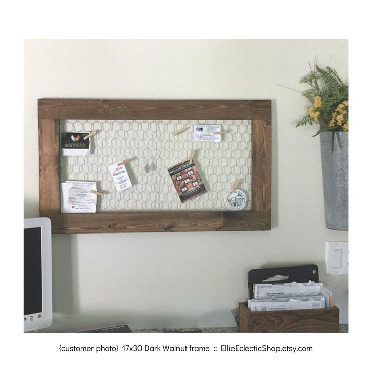 a bulletin board is hanging on the wall next to a computer and flower pot with yellow flowers