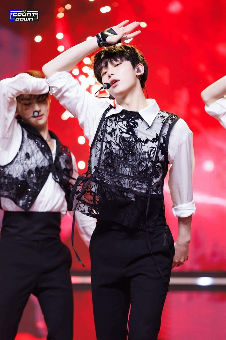 two young men in black and white outfits on stage with their hands behind their head