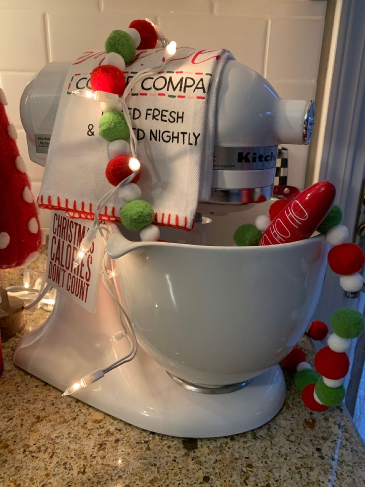 a white bowl with christmas decorations around it on a counter top next to a blender