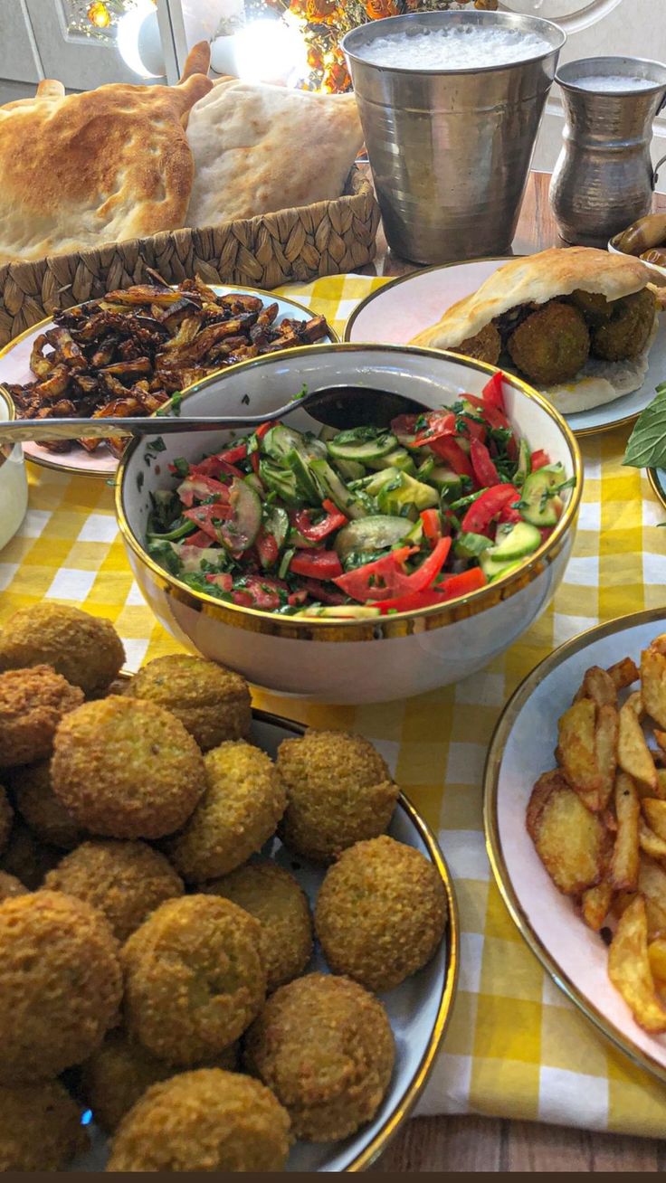 a table topped with plates of food next to bread and other dishes filled with vegetables