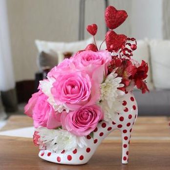 a vase filled with pink roses and white flowers sitting on top of a wooden table