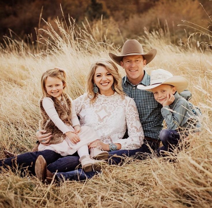 a man and two children are sitting in the tall grass with their cowboy hats on