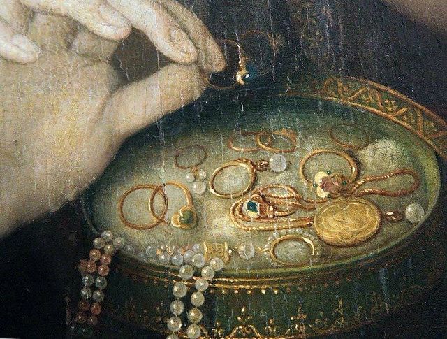 a close up of a painting with jewelry on it's display case and hands