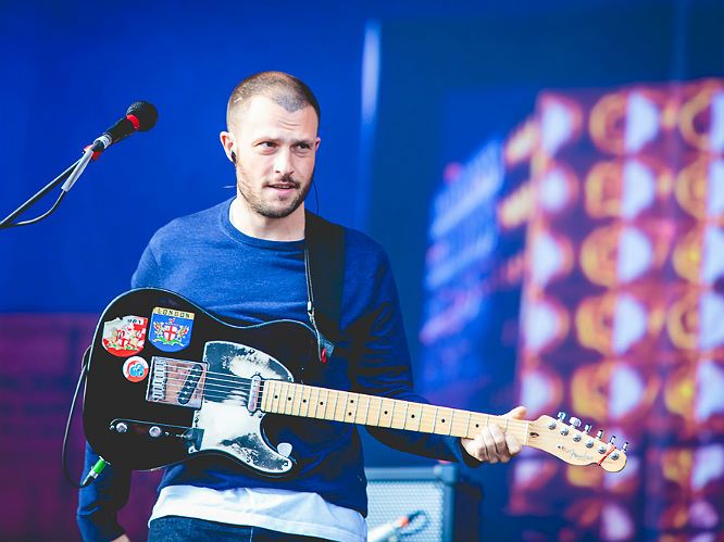 a man holding a guitar while standing in front of a microphone