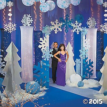 a man and woman standing in front of snow themed stage set for a christmas party