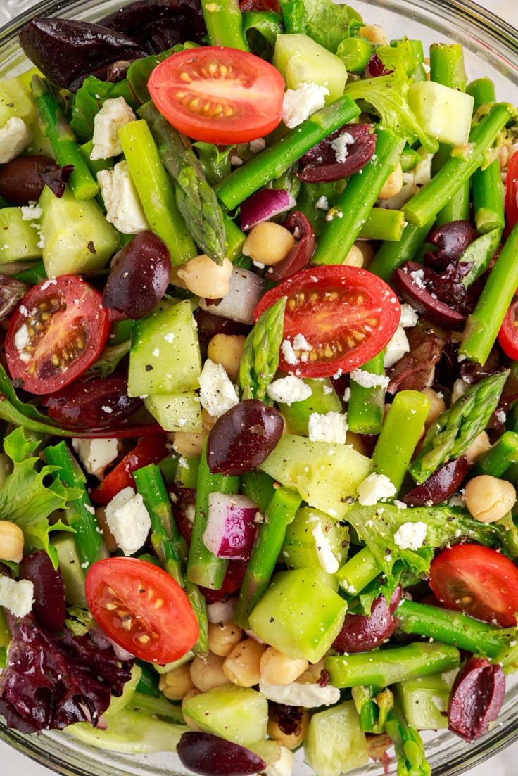 a salad with asparagus, olives, tomatoes and feta cheese