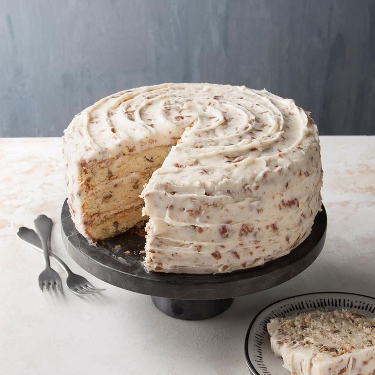 a frosted cake sitting on top of a black plate