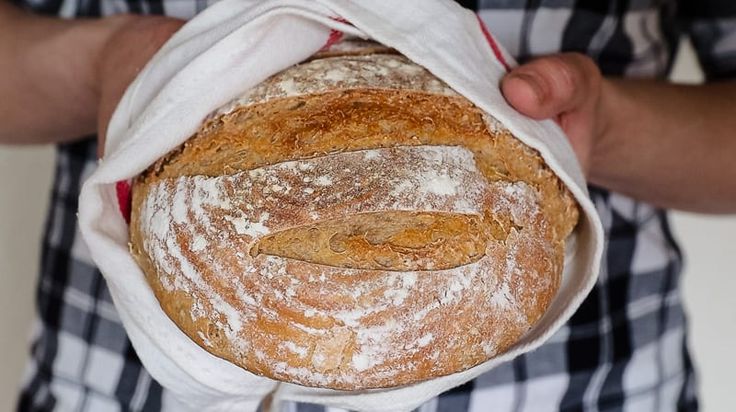 a close up of a person holding a loaf of bread in their hands and covering it with a cloth