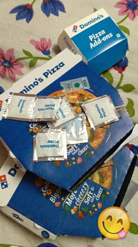 there are three boxes of dominos and two packs of pizza sitting on the bed