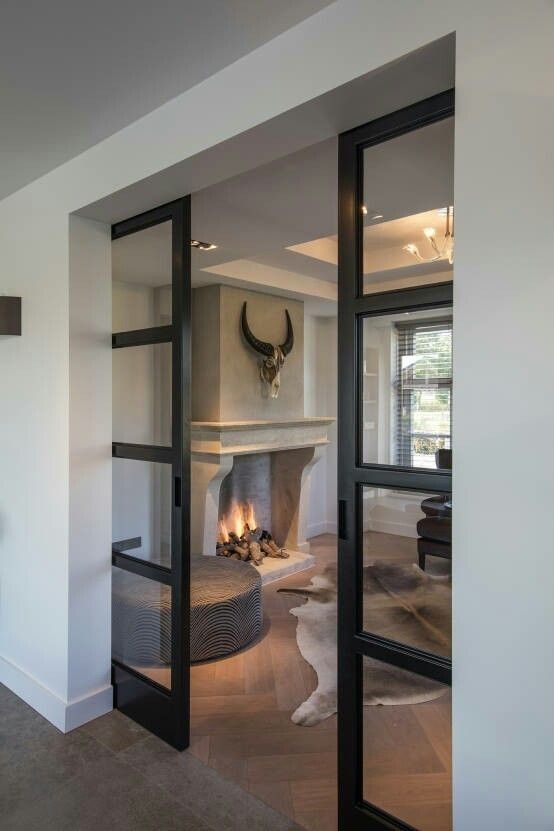 an open living room door with a fireplace in the center and large windows on both sides