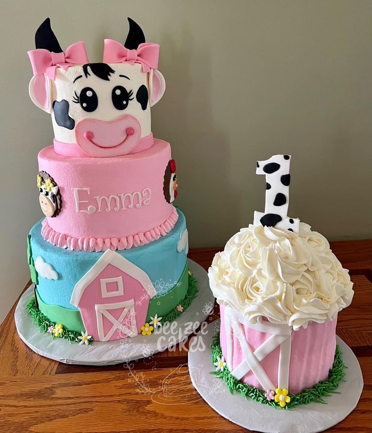 two cakes decorated to look like farm animals, one with a cow and the other with a barn