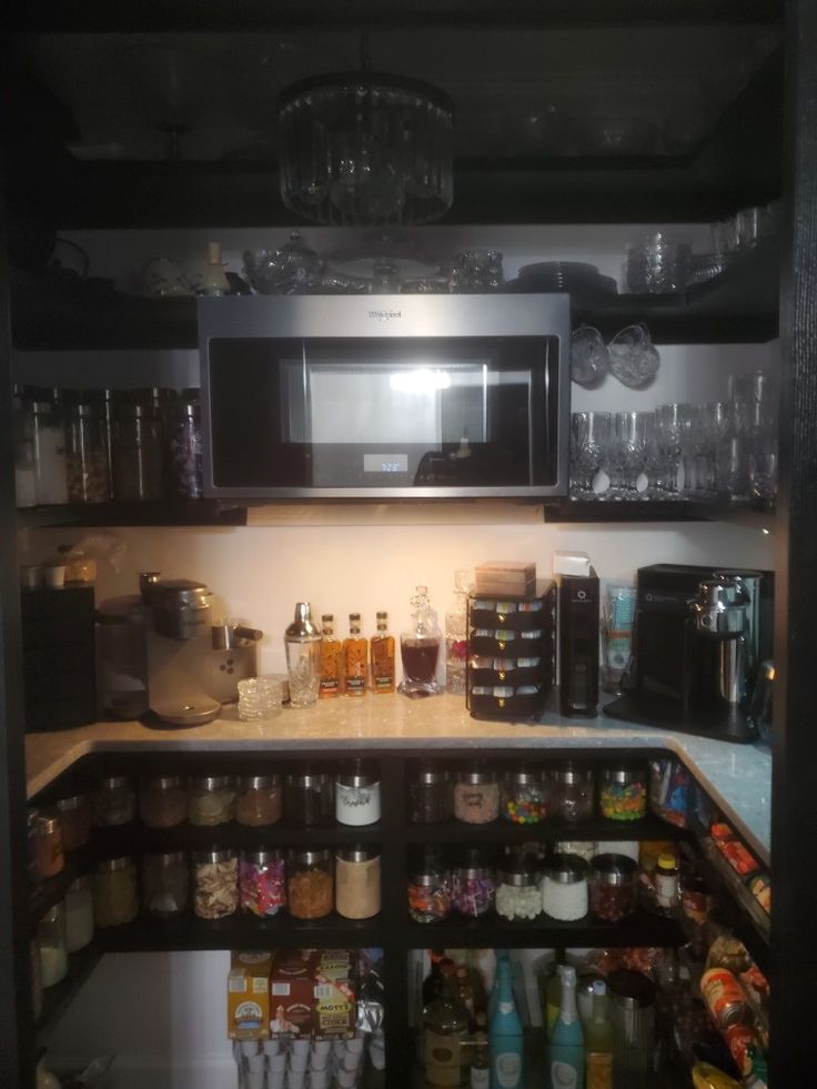 an organized pantry with lots of spices and condiments on the shelves, including a microwave