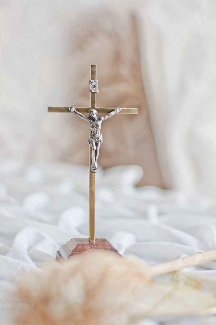 a crucifix on a bed with white sheets and pillows in the background