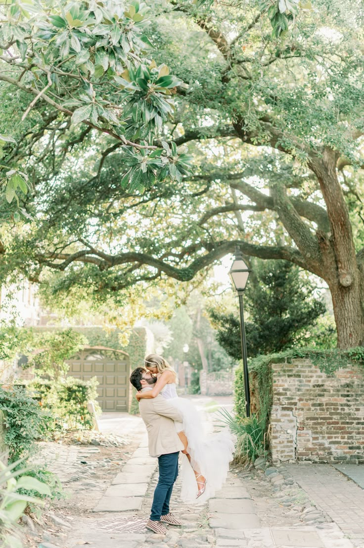 a bride and groom hugging under an oak tree at their wedding in charleston, south carolina