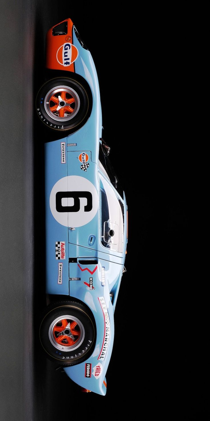 a blue race car hanging from the side of a wall in front of a black background