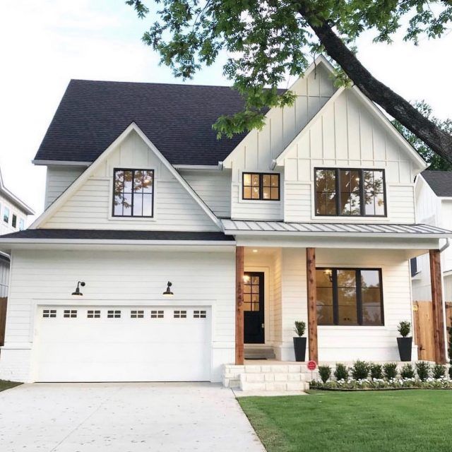 a large white house with two story windows and black shutters on the front door