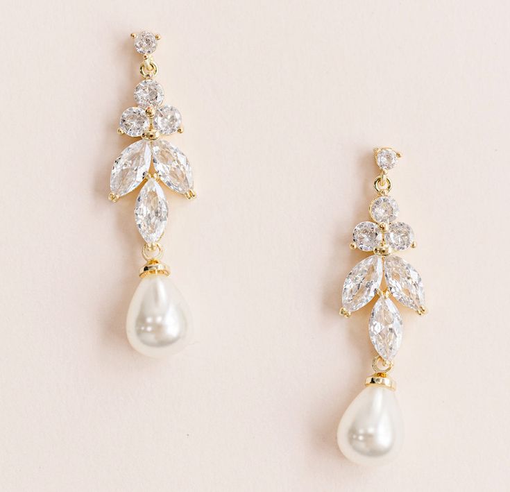 two pairs of earrings with white pearls and crystal leaves on top of each earring