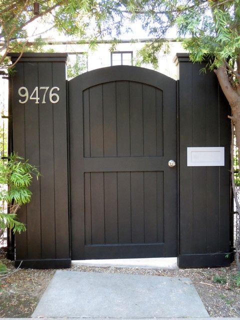 a black gate that has the number 9416 on it and is next to a tree