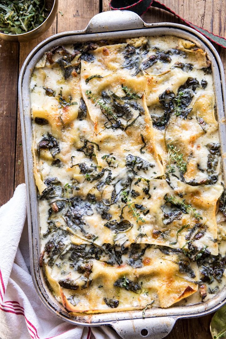 a casserole dish with spinach and cheese in it on a wooden table