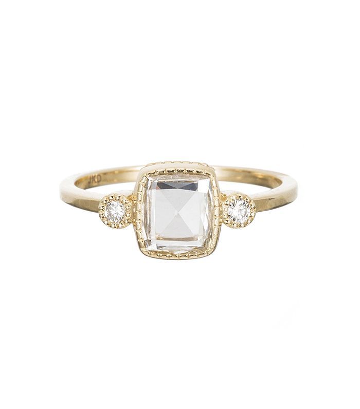 an 18k yellow gold ring with a square cut diamond and three small diamonds