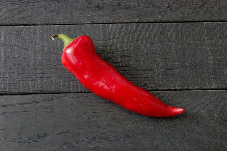 a red pepper sitting on top of a wooden table