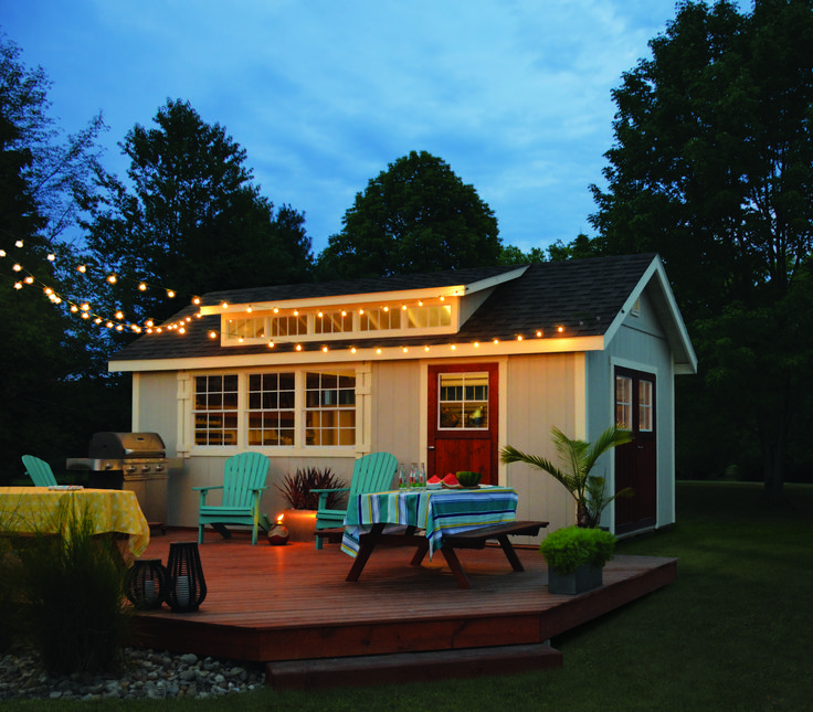 a small house with lights on the roof and patio furniture set up in front of it