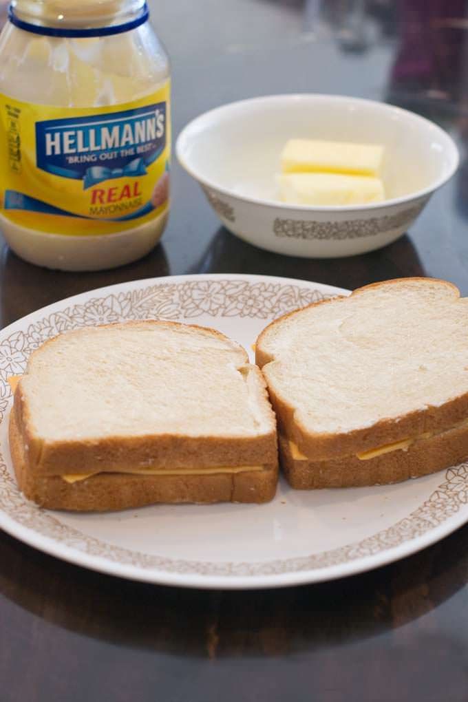 two slices of bread on a plate with butter and mayonnaise in the background