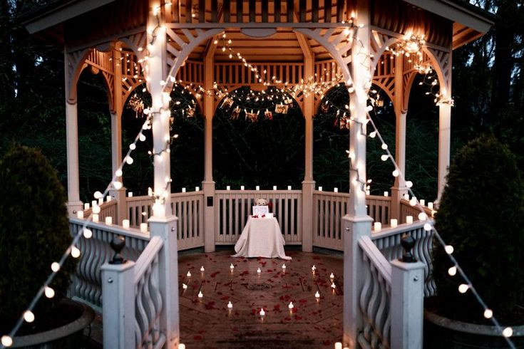 a gazebo covered in lights with a white table cloth on it's side