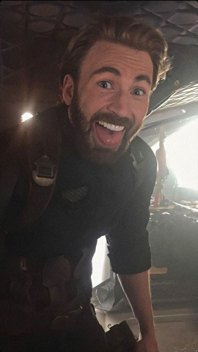 a man with a beard is smiling in front of a car