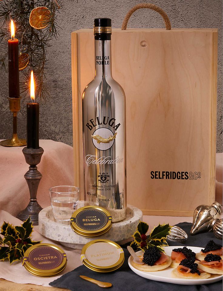 a bottle of booze sitting on top of a table next to plates and candles