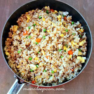 a pan filled with rice and vegetables on top of a wooden table