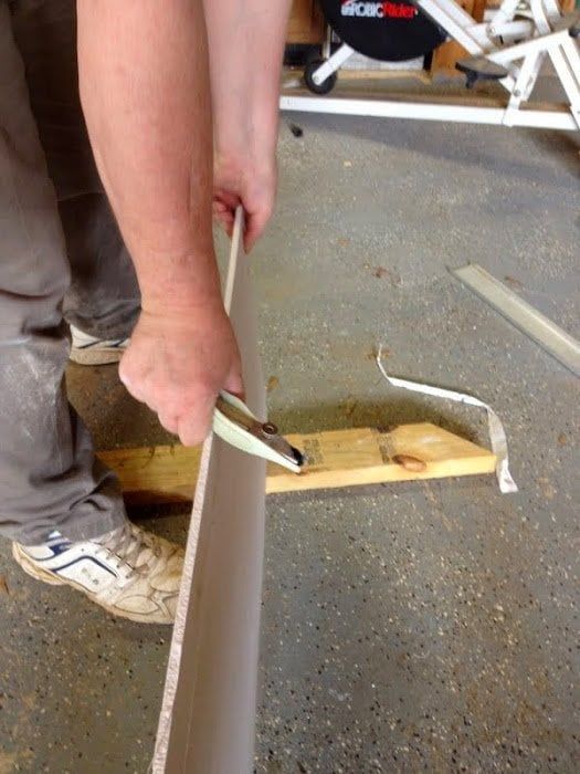 a man is using a pair of scissors to cut the edge of a piece of wood