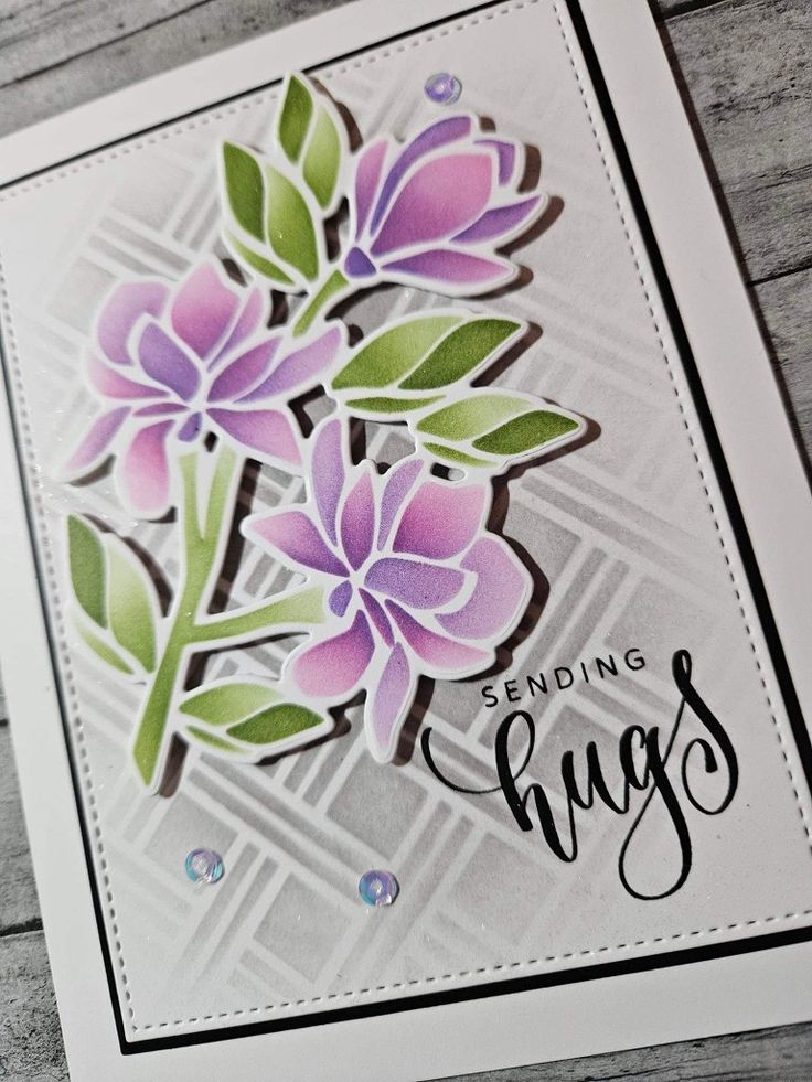 a close up of a card with flowers and words on the front, which reads sending hugs