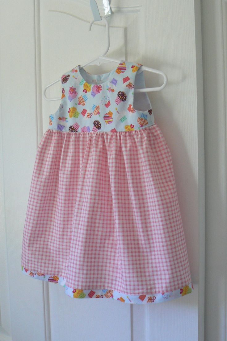 This pale blue bodice of this dress is covered in bright colored cupcakes. The skirt is a pink and white gingham with a cupcake trim around the bottom. This would be a fun party dress or any occasion dress for your little girl. The bodice is lined in a pale blue fabric with a pink button on the back. The fabric has been washed and dryed and the seams are surged. Sweet Gingham Dress With Ruffles, Sweet Gingham Cotton Dress, Playful Sleeveless Gingham Dress, Playful Gingham Dress With Ruffles, Playful Gingham Dress For Playtime, Colorful Cupcakes, Cupcake Dress, Pink Gingham, Little Girl Dresses