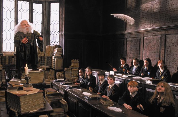 harry potter in the classroom with his staff and students looking at books on desks