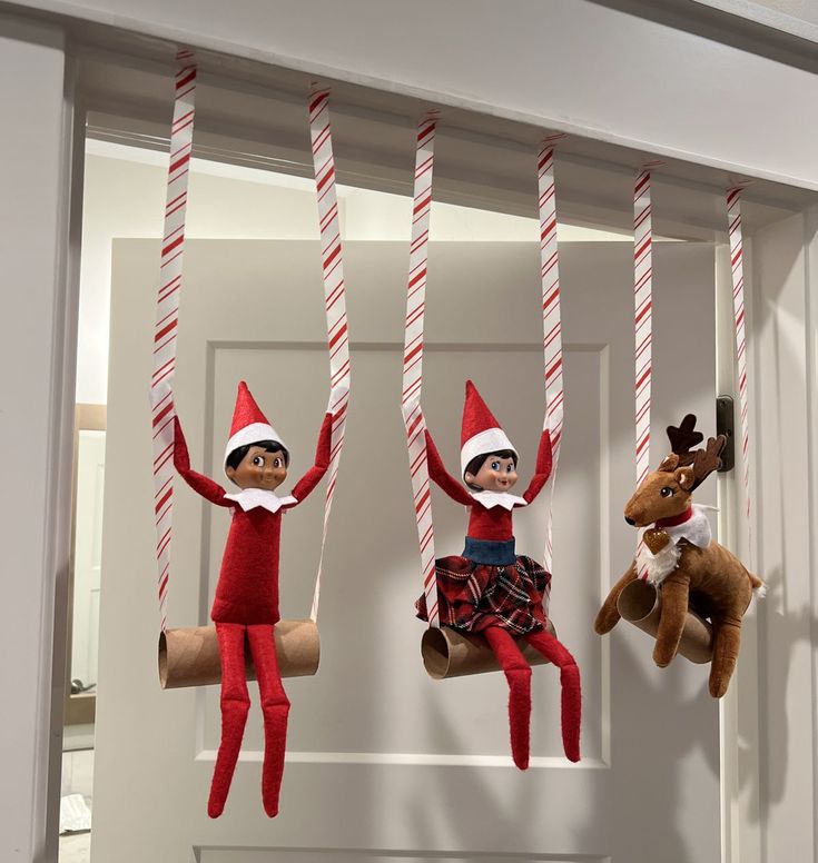 three elfs hanging from the ceiling with candy canes