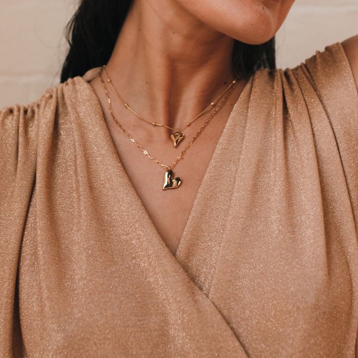 Our Lovely Heart Necklace is a dainty necklace that features a chic heart pendant drop. This gorgeous necklace is stainless steel with gold plating, and it will not tarnish with minimal care. This lovely, minimalist necklace will be something you wear daily! 18K Gold Plating on Stainless Steel. Waterproof. About 15.5in + 2in extension, pendant is about 1/2 in Minimalist Delicate Chain Necklace With Heart Pendant, Minimalist Gold-plated Charm Necklace With Heart Charm, Minimalist Gold Plated Heart Charm Necklace, Minimalist Gold-plated Heart Charm Necklace, Minimalist 14k Gold Filled Heart Pendant Necklace, Minimalist Heart Pendant Chain Necklace, Dainty Stainless Steel Chain Necklace, Gold Heart-shaped Layered Necklace With Clavicle Chain, Trendy Gold Heart Pendant Charm Necklace