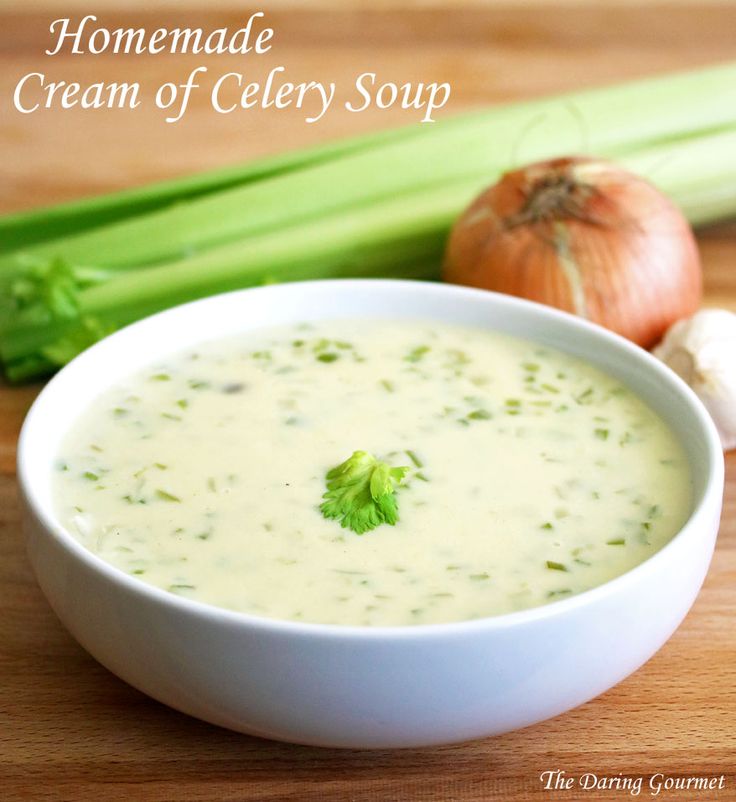 a white bowl filled with soup next to celery and an onion on a cutting board