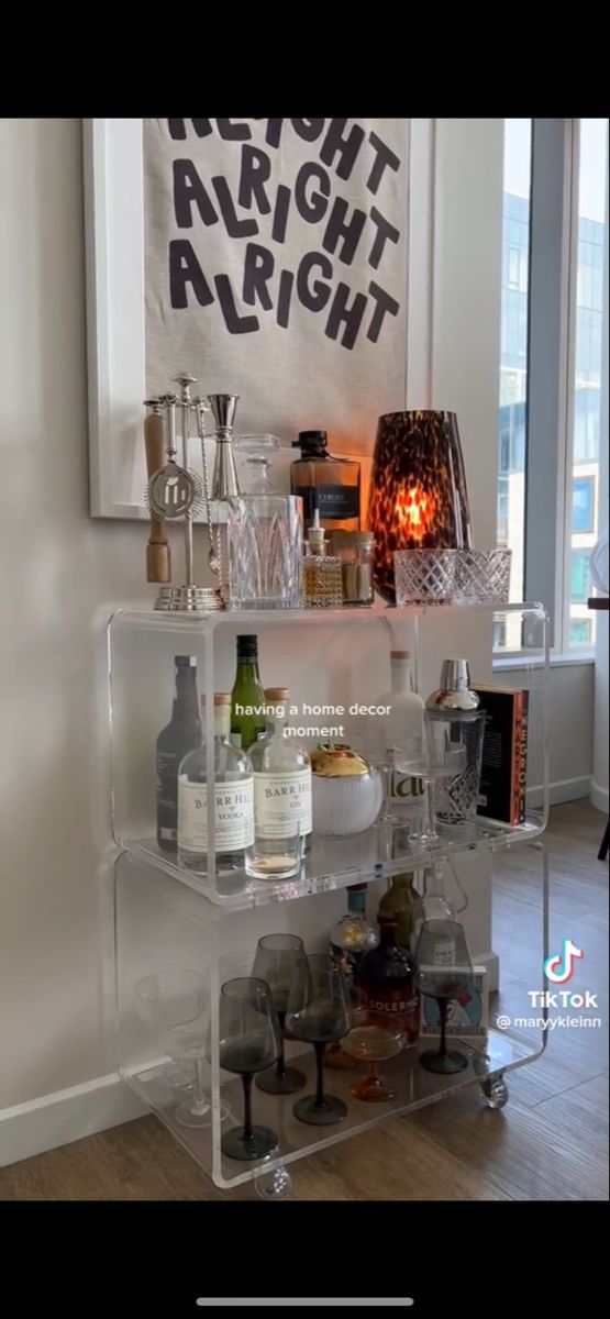 a shelf filled with bottles and glasses next to a window