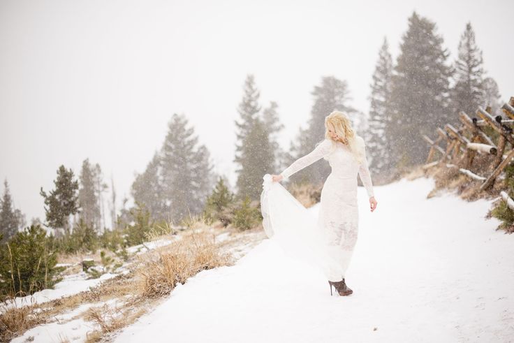 a woman in a white dress is walking through the snow