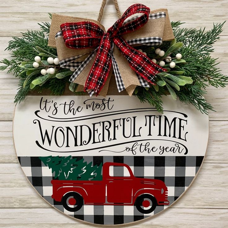 a red truck with a christmas tree on the front is hanging from a sign that says it's the most wonderful time of the year